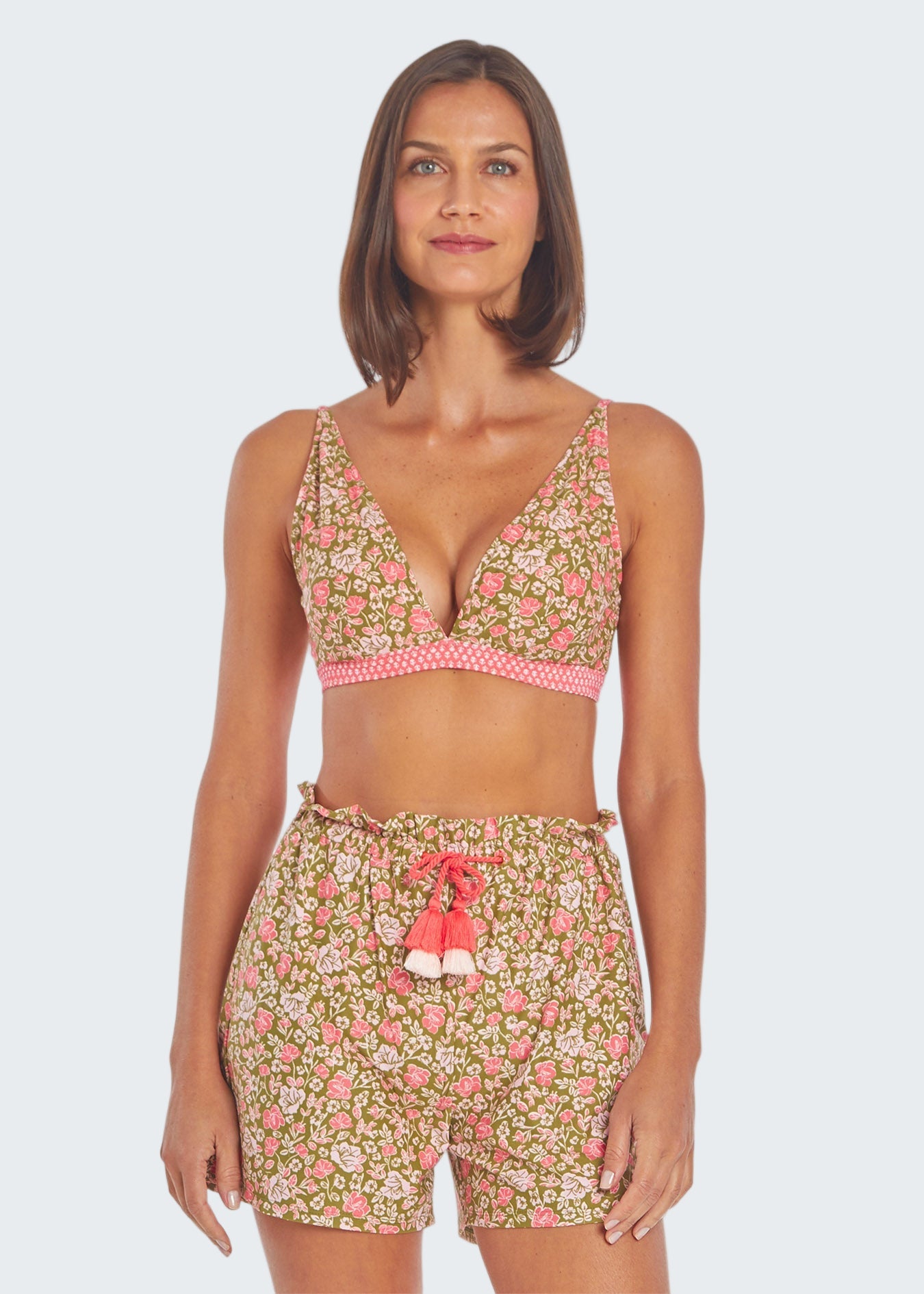 Woman wearing a floral two-piece swimsuit with pink accents on a white background