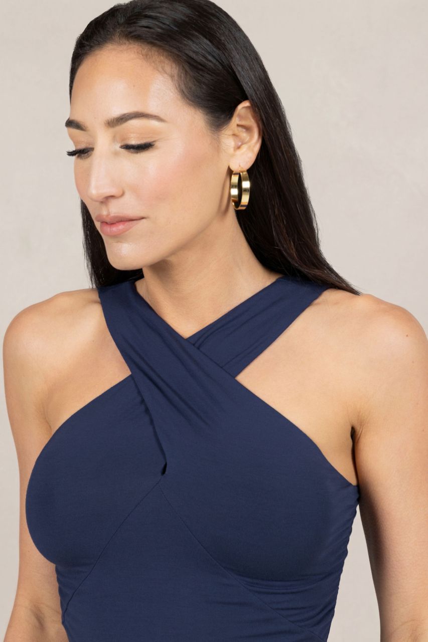 Woman wearing a navy blue halter dress with a plain background
