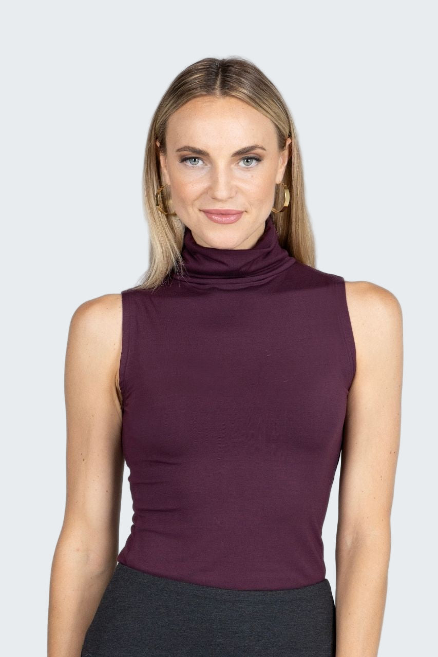 Woman wearing a sleeveless purple top against a gray background