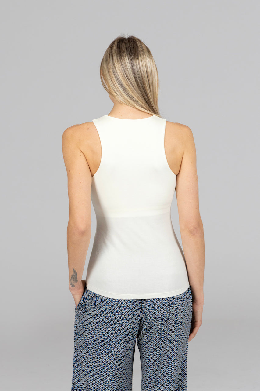 Person wearing a white sleeveless top and patterned pants on a gray background