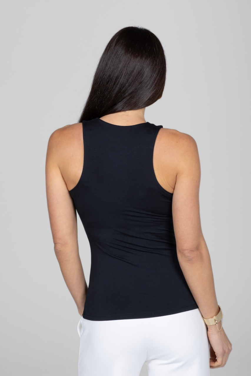 Person wearing a black sleeveless top and white pants on a gray background