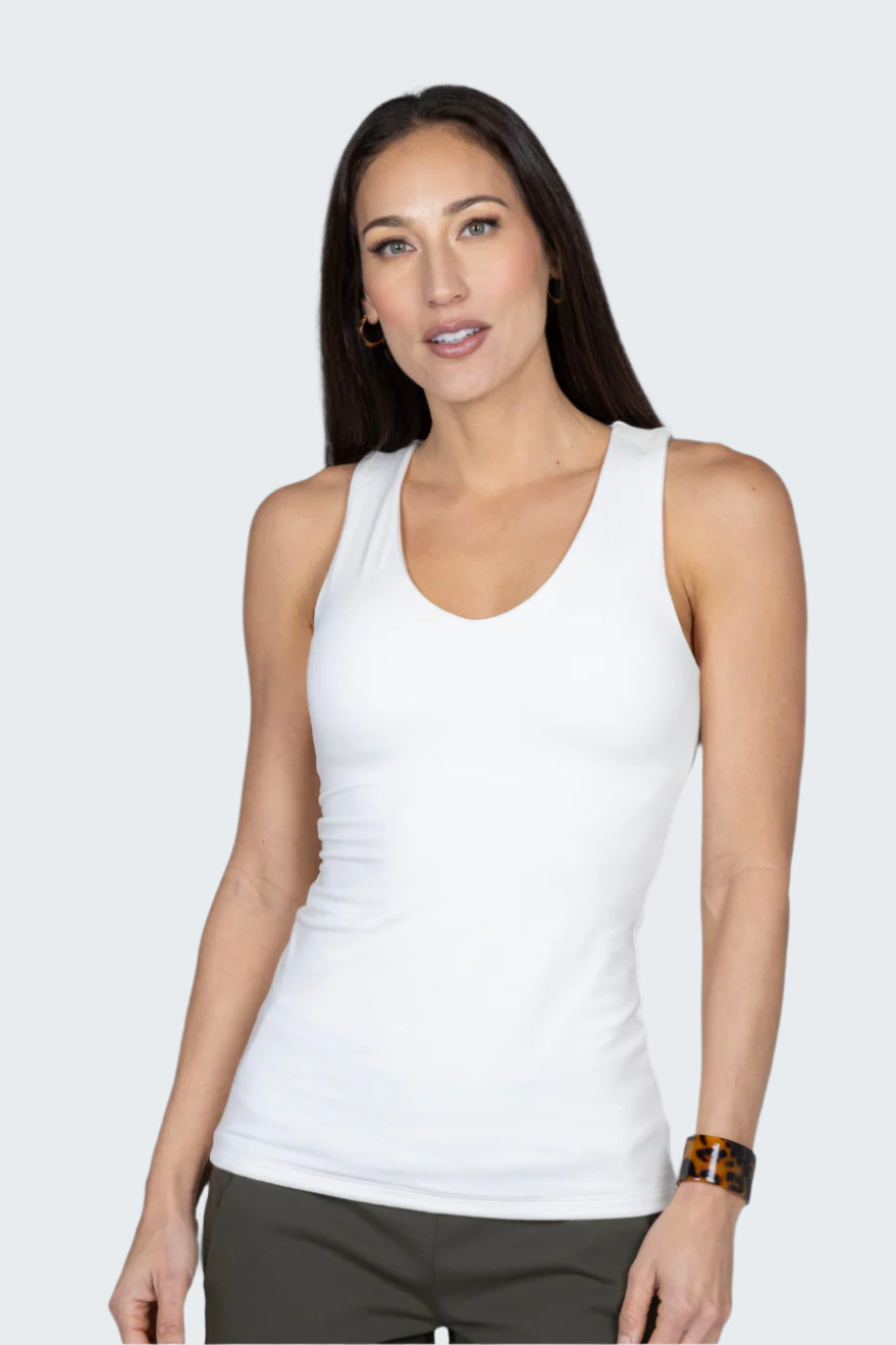 Woman wearing a white tank top against a plain background