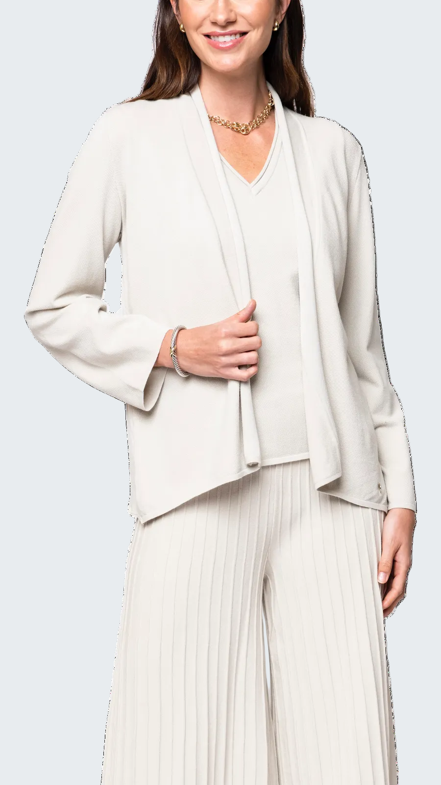 Woman wearing a light-colored outfit with a jacket and pants on a white background
