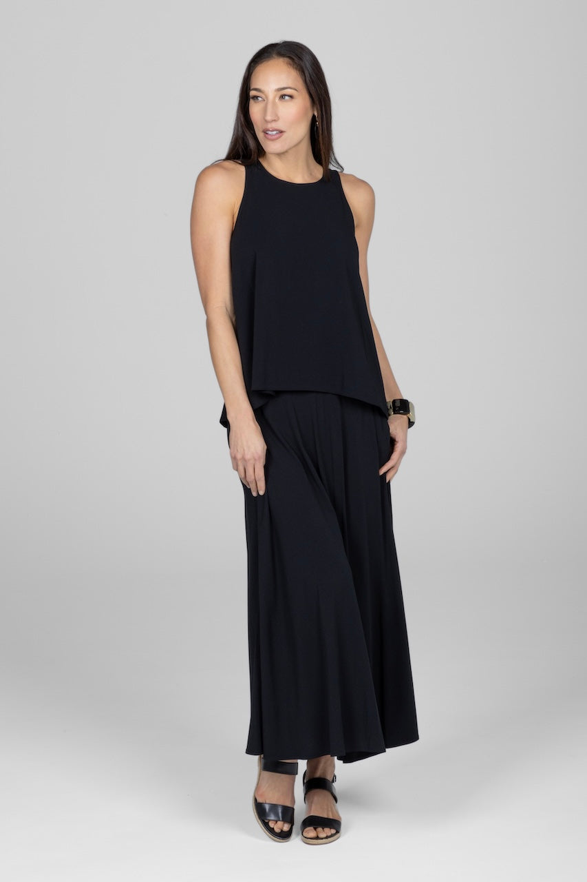 Woman wearing a black sleeveless top and wide-leg pants on a white background