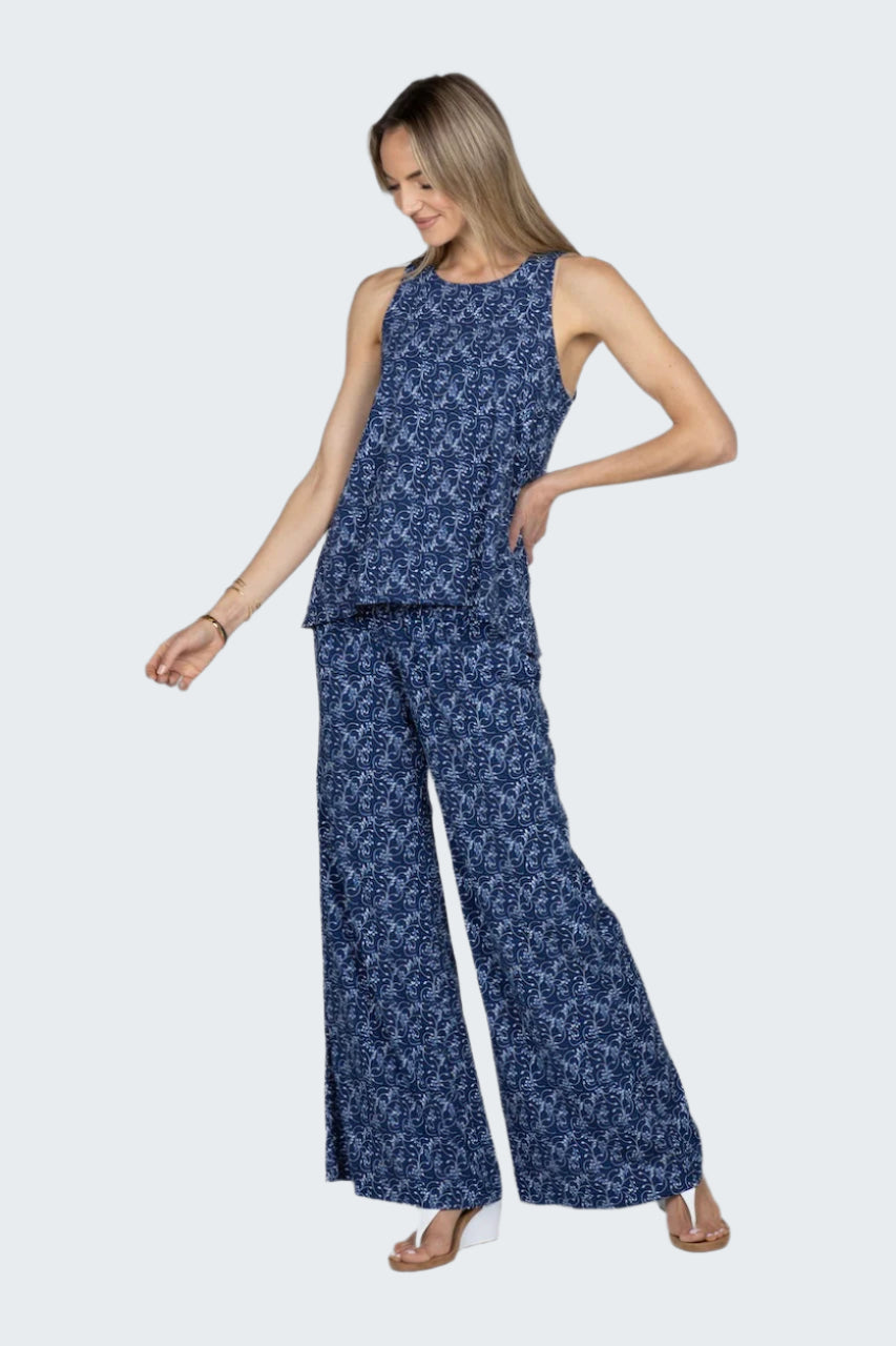 Woman wearing a blue floral sleeveless top and wide-leg pants on a white background