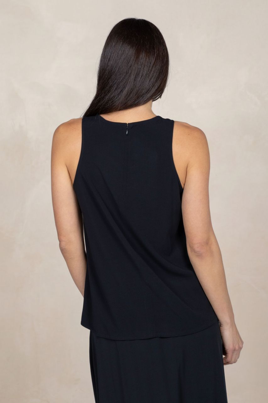 Person wearing a black sleeveless top against a beige background