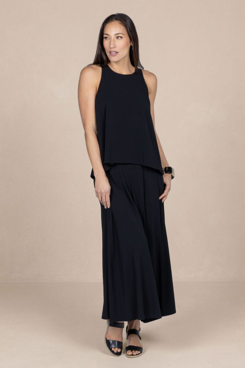 Woman wearing a black sleeveless top and wide-leg pants on a beige background