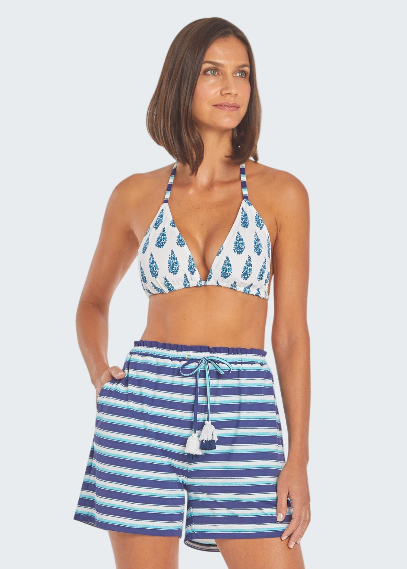 Woman wearing a blue and white patterned bikini with matching shorts on a white background