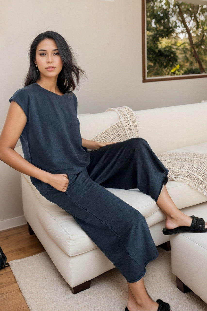 Woman in a navy blue outfit sitting on a white couch in a home setting.