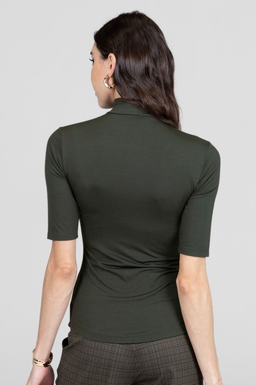 Woman wearing a green polo shirt on a gray background