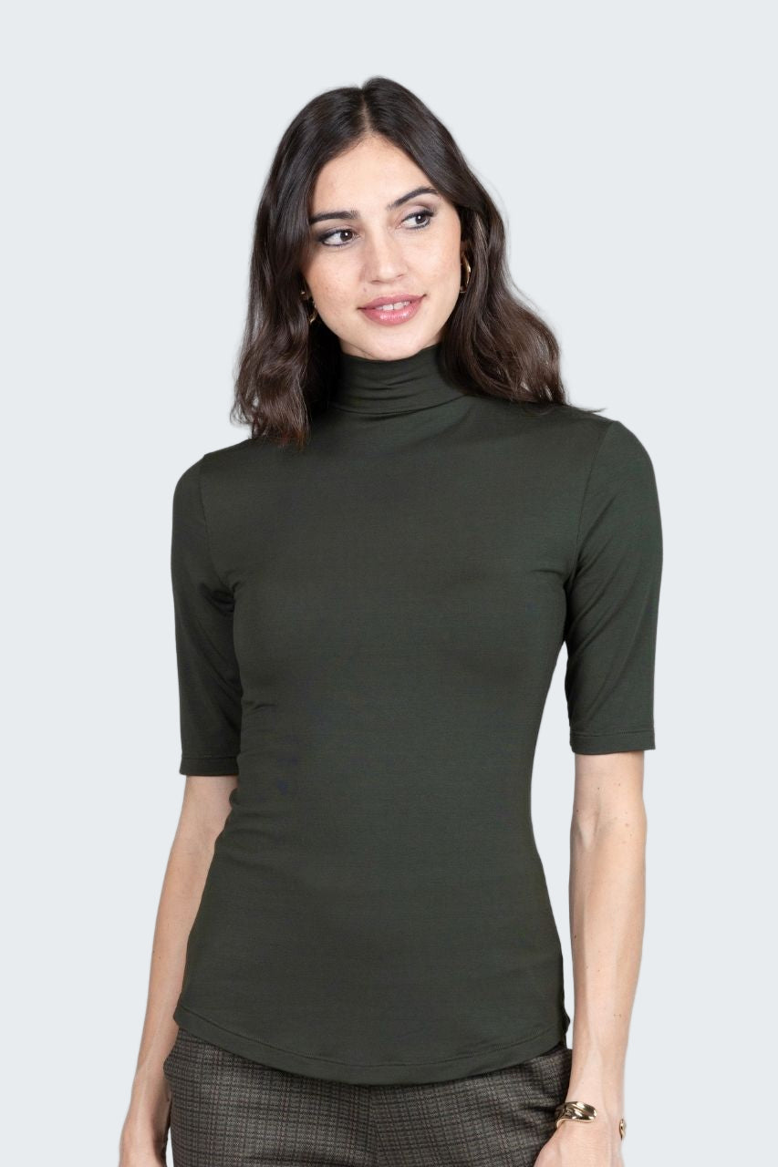 Woman wearing a green turtleneck shirt against a plain background