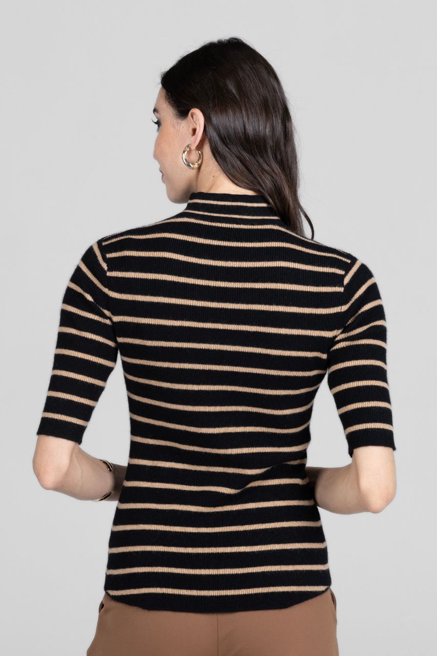 Woman wearing a black and beige striped shirt against a gray background