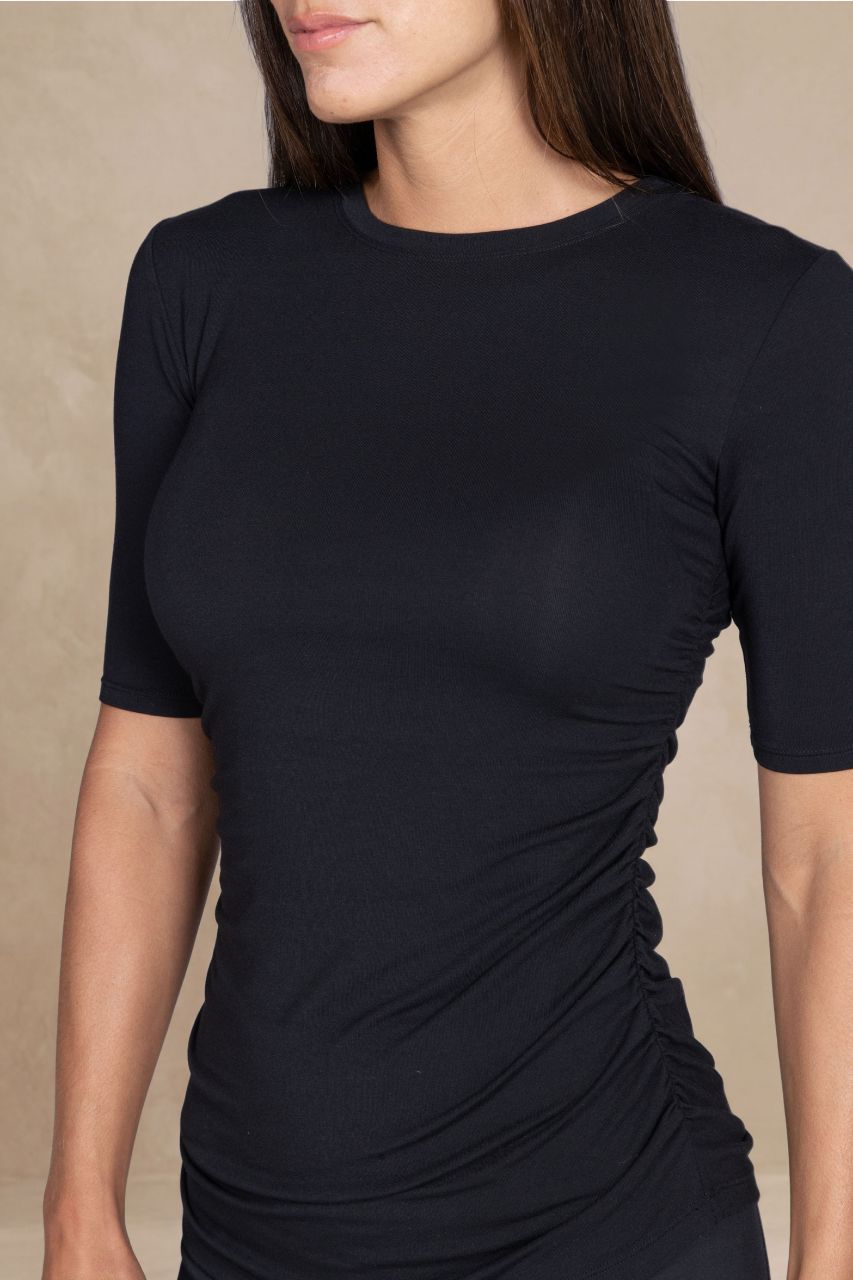 Black short-sleeve top worn by a person on a beige background