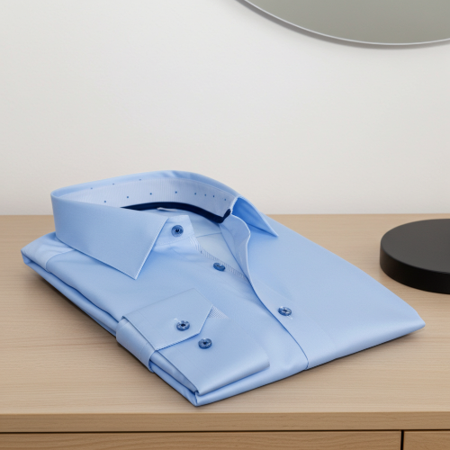 Folded light blue dress shirt on a wooden surface with a neutral background