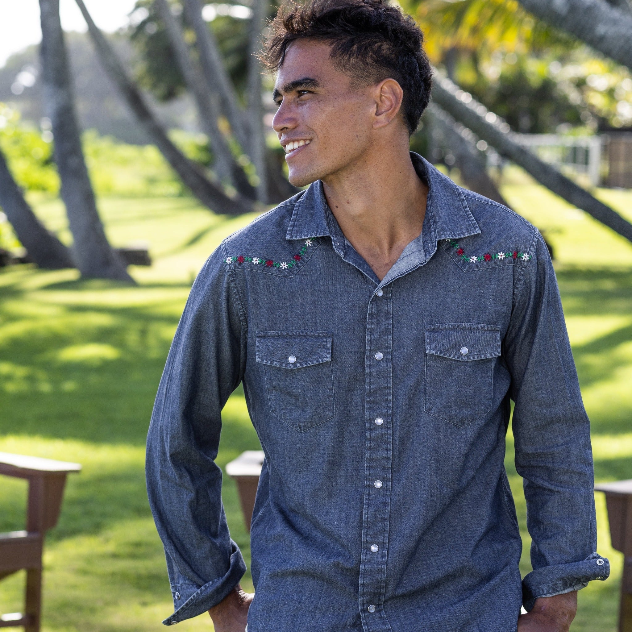 Man wearing a blue denim shirt with embroidered details outdoors