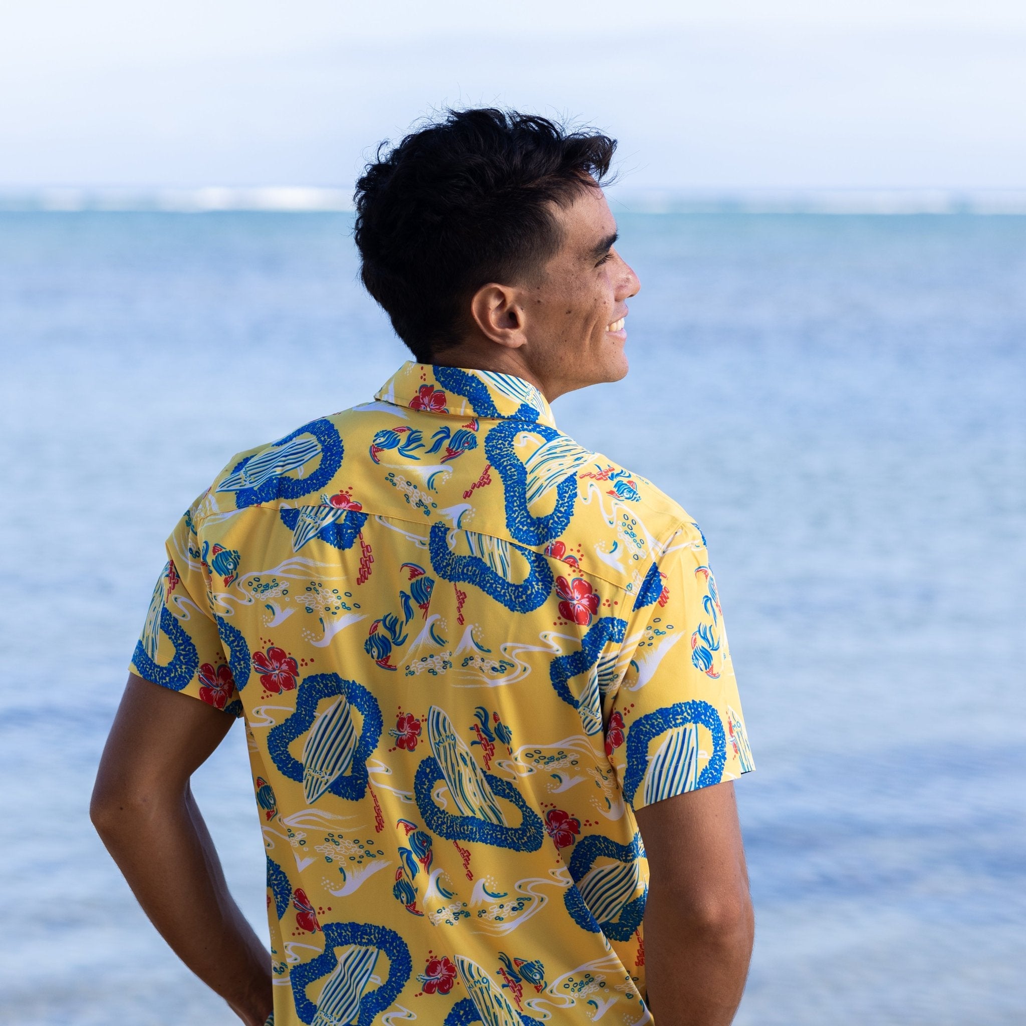 Man wearing a colorful shirt with a pattern, standing by the ocean.