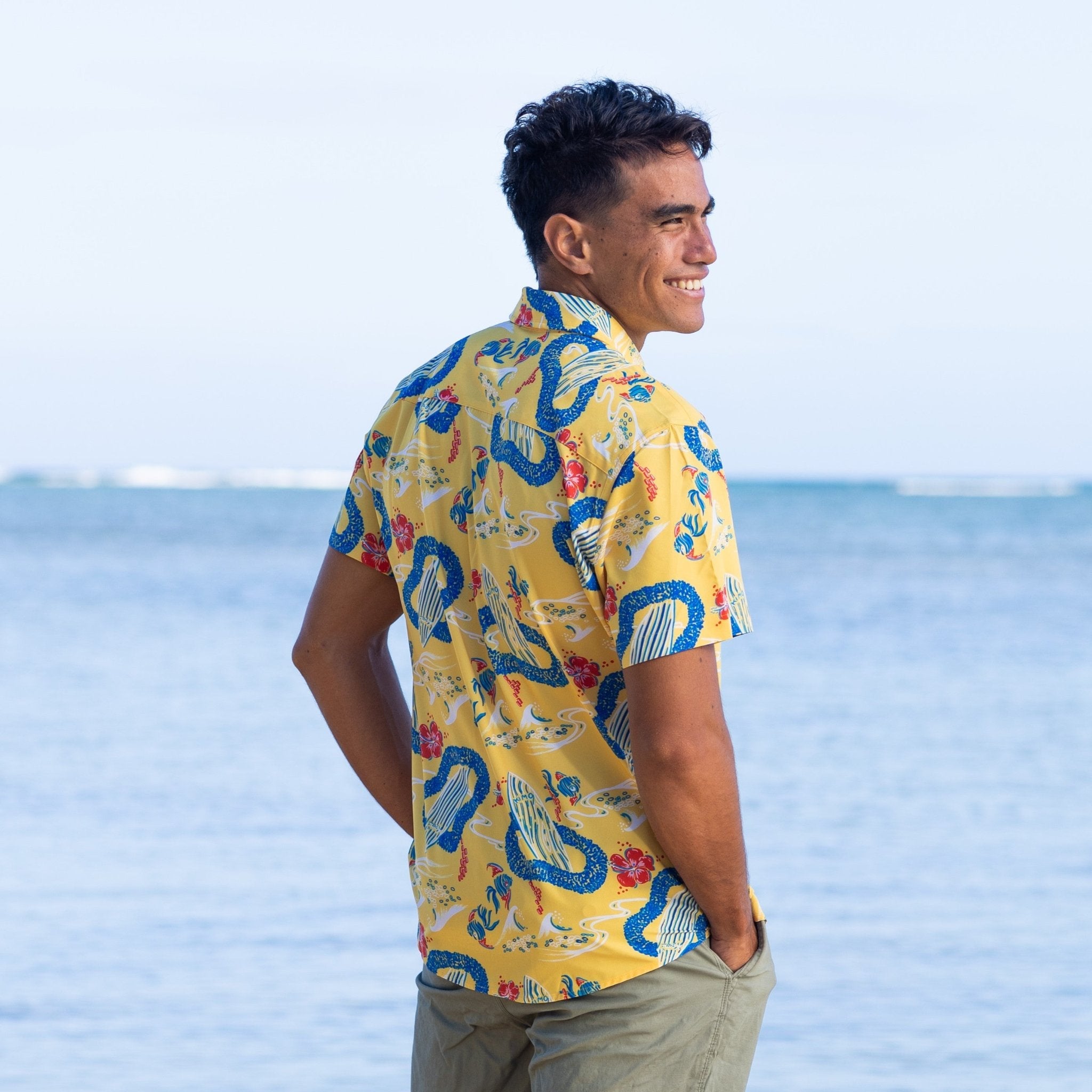 Man wearing a colorful shirt with a dragon pattern by the ocean
