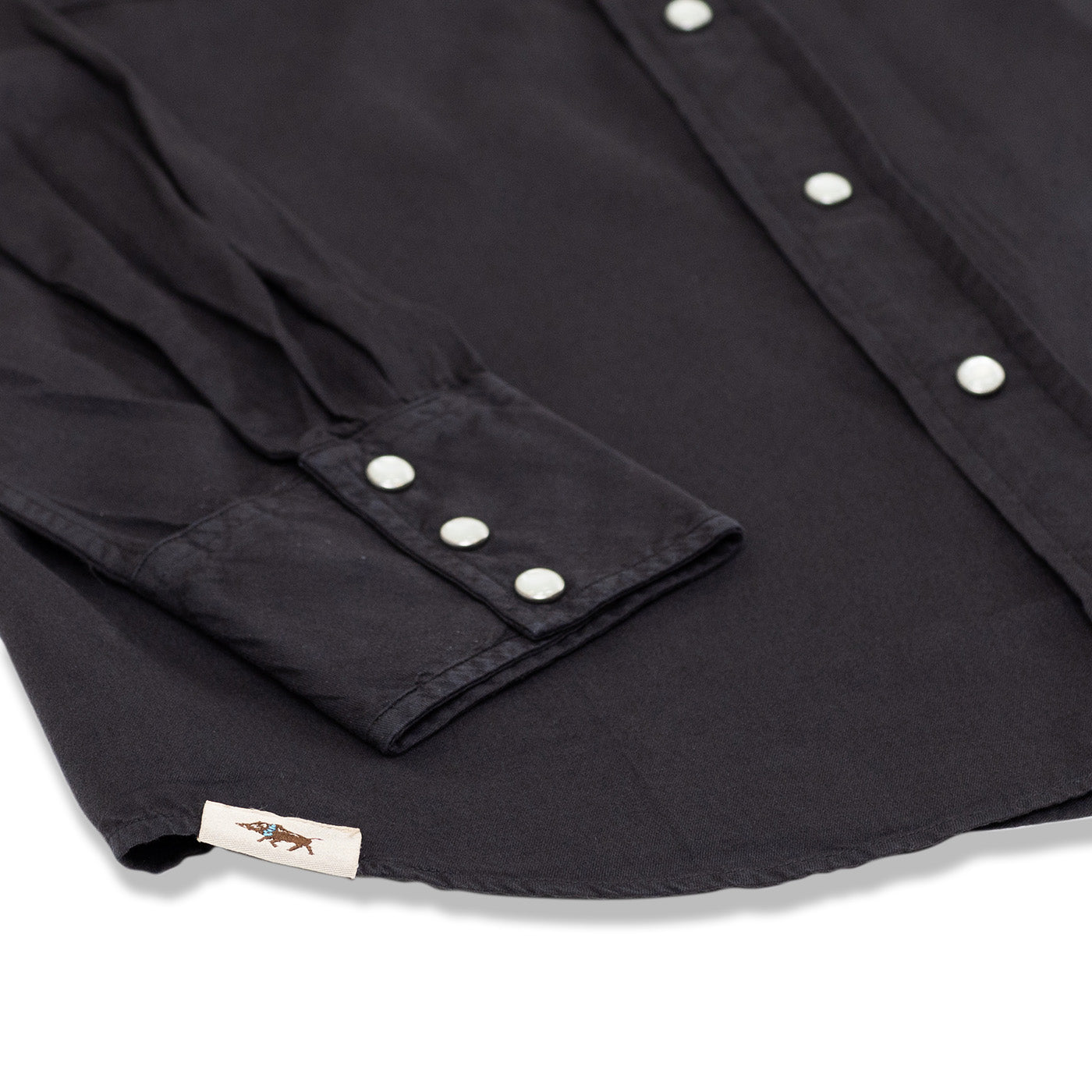 Close-up of a black shirt with buttons and a visible brand label on a white background