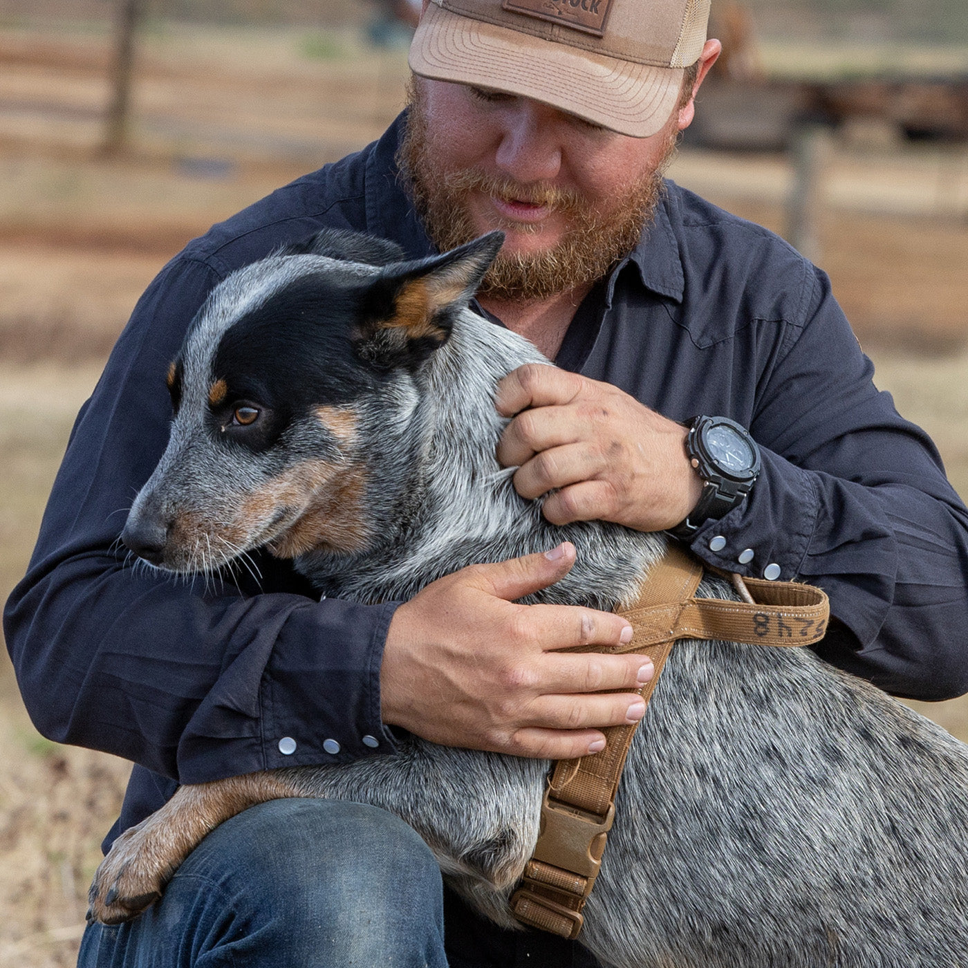 Man holding a dog outdoors with a blurred background