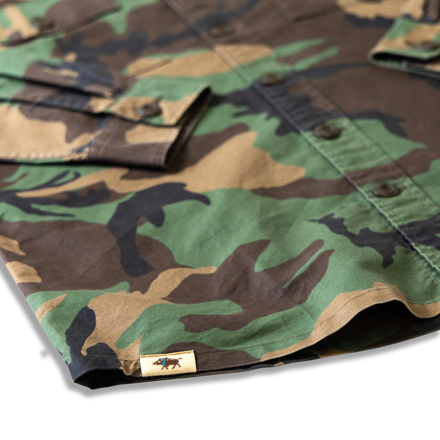 Close-up of a camouflage-patterned shirt with a brand logo on a white background