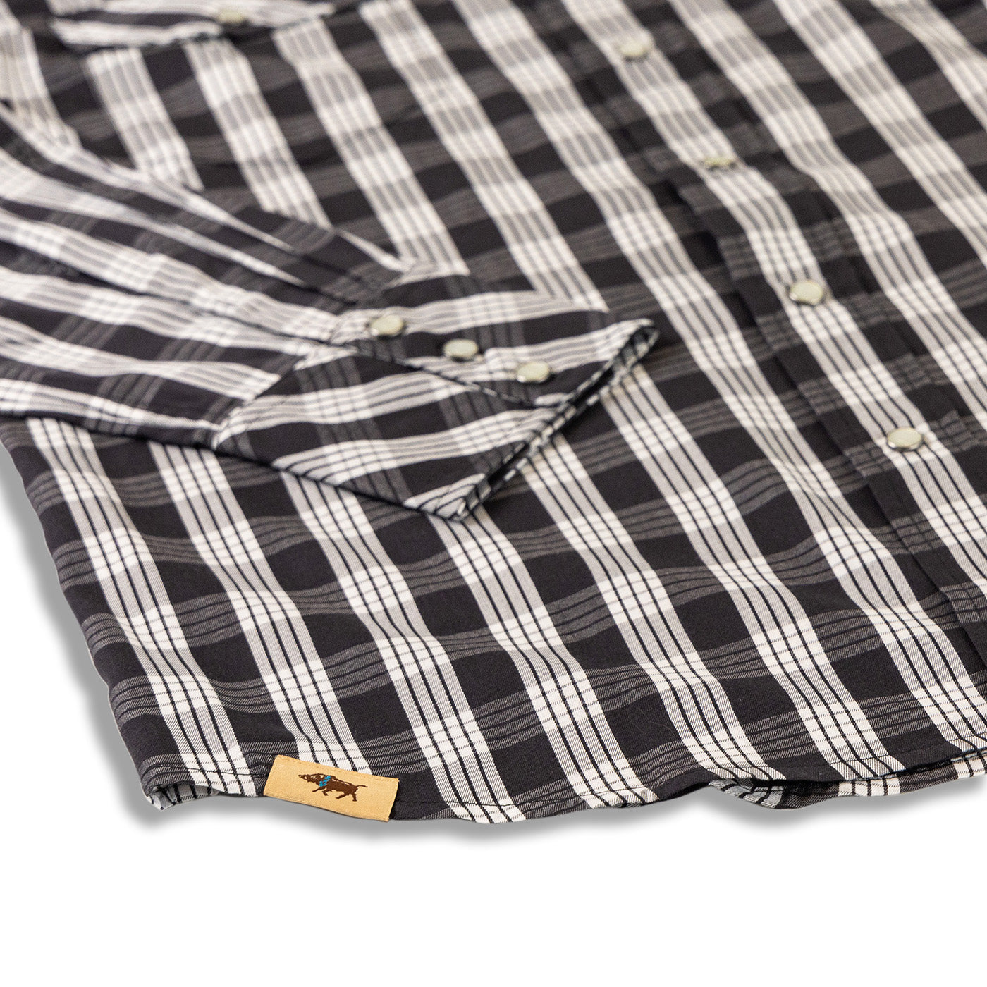 Close-up of a black and white checkered shirt with a brand label on a white background