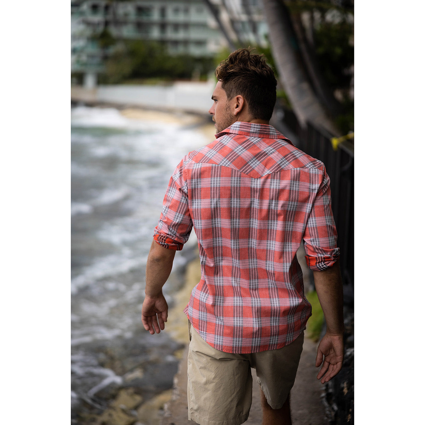 Man wearing a red and white checkered shirt by a waterfront