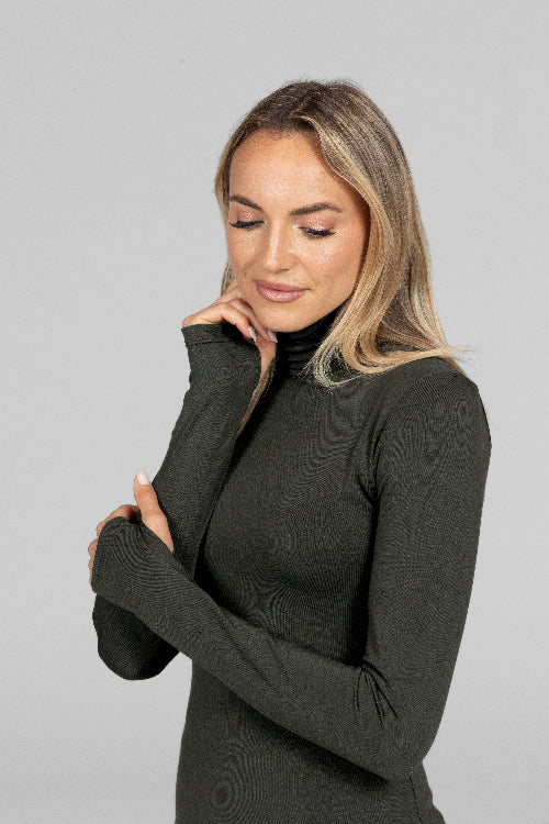 Woman wearing a black long-sleeve top against a gray background