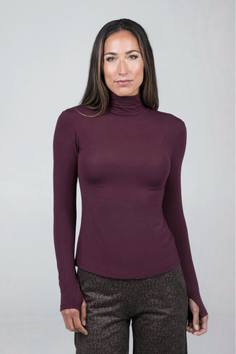 Woman wearing a purple turtleneck sweater against a plain background
