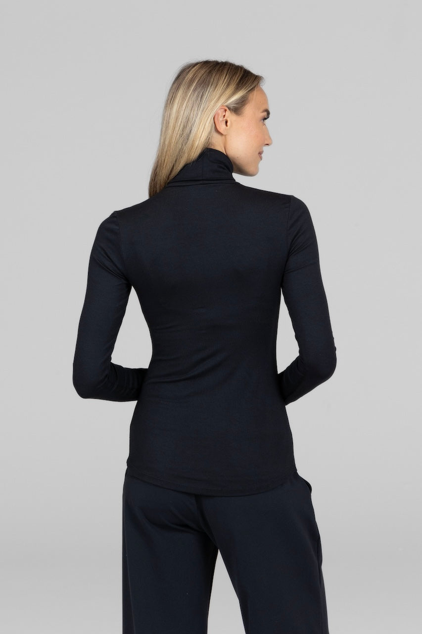 Person wearing a black long-sleeve top and pants on a gray background