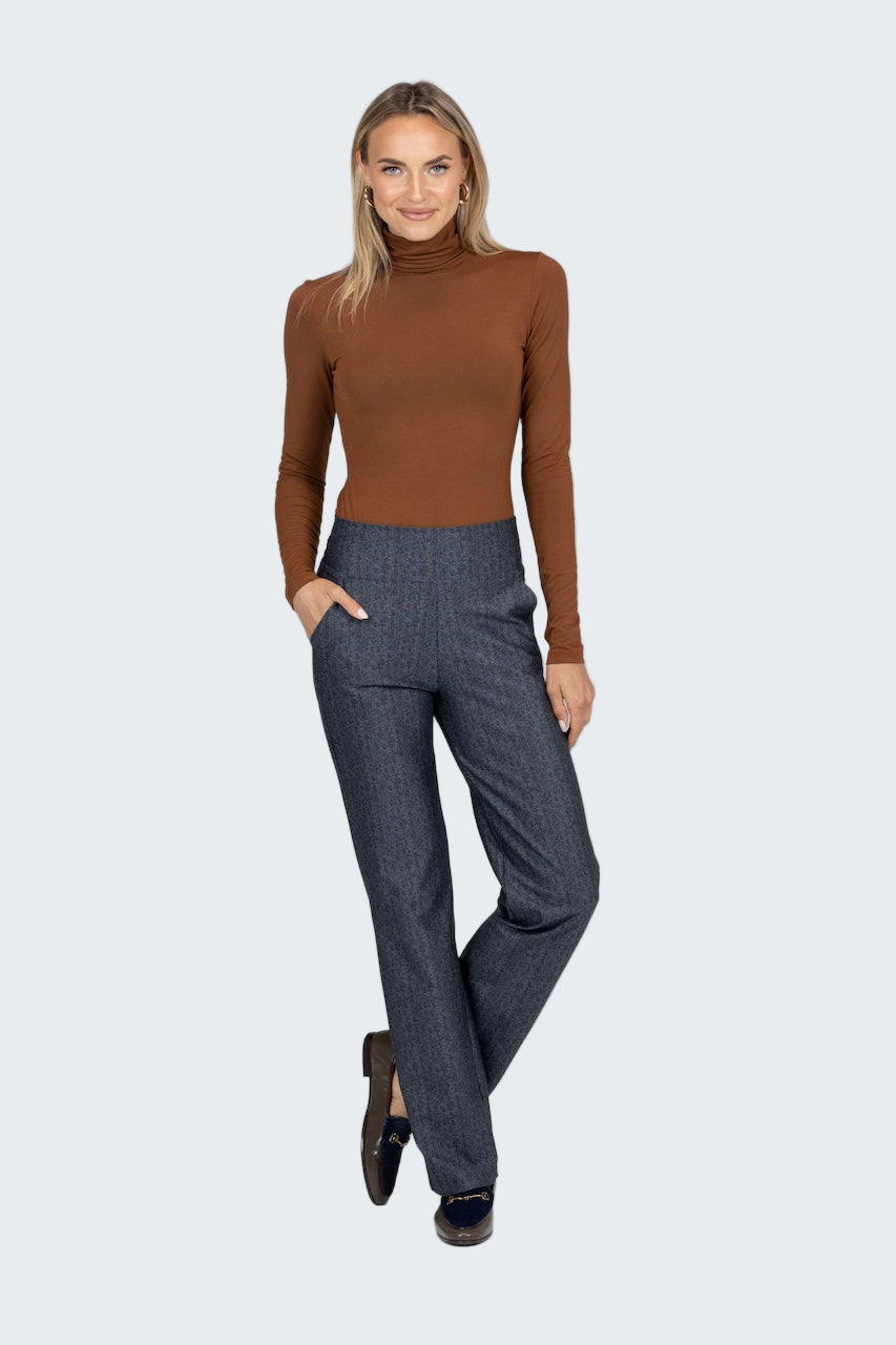 Woman wearing a brown turtleneck and gray pants on a white background