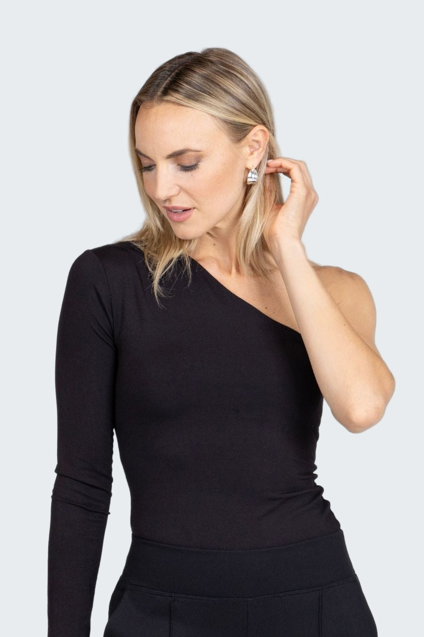 Woman wearing a black one-shoulder top against a plain background