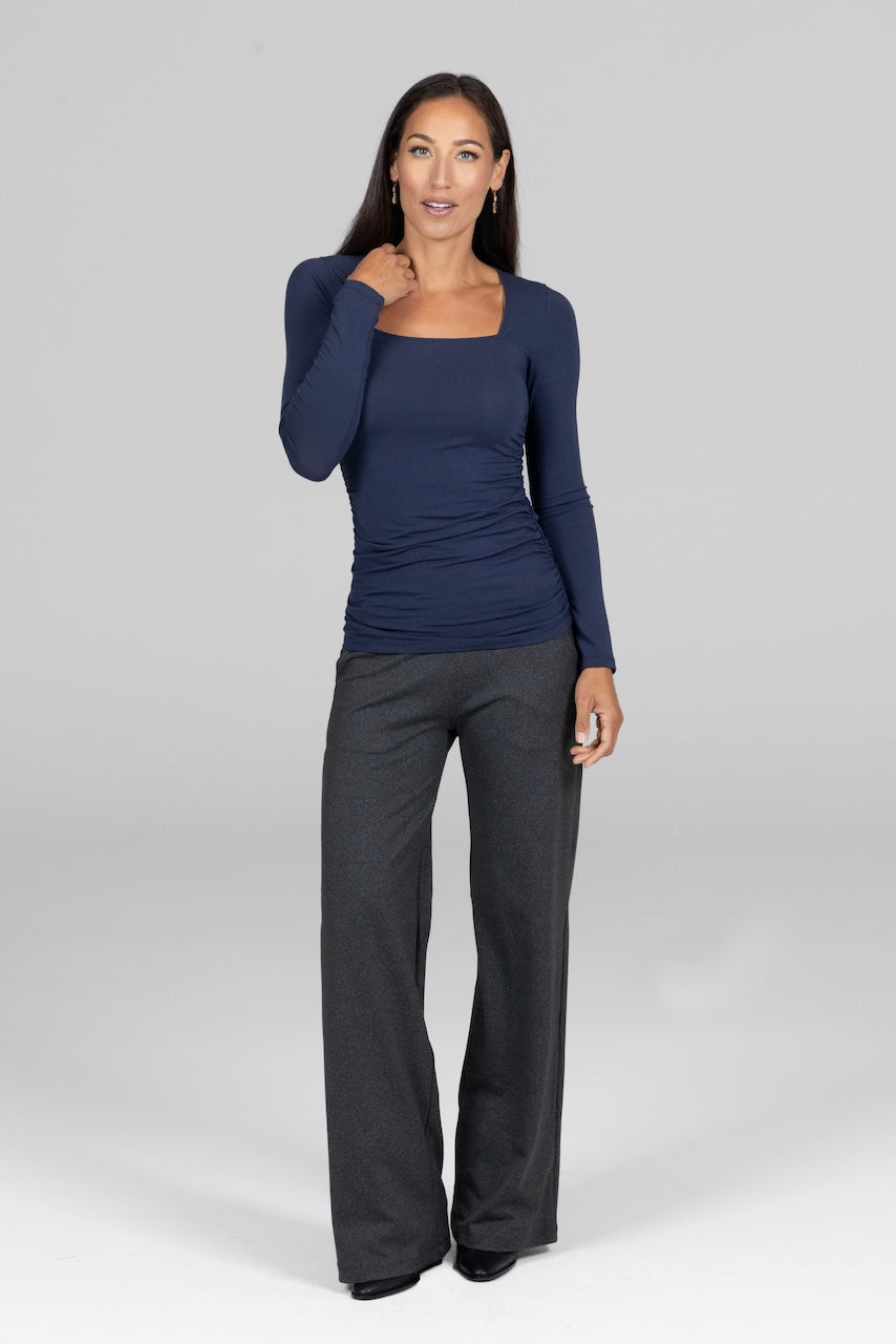 Woman wearing a navy long-sleeve top and gray pants on a white background