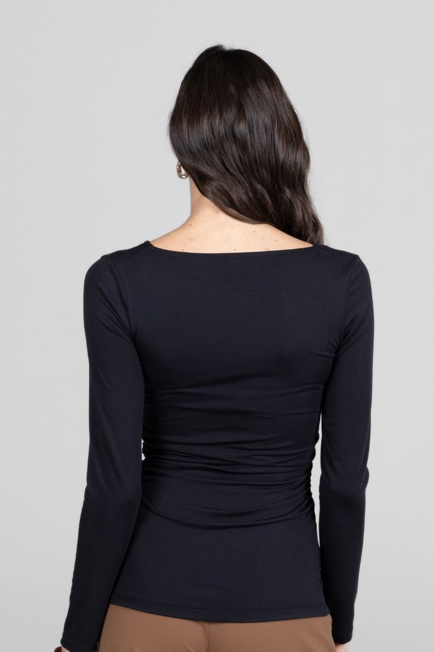 Black long-sleeve top worn by a person on a gray background