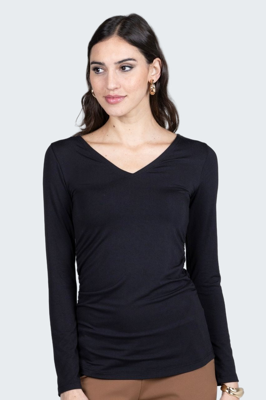 Woman wearing a black long-sleeve top against a gray background