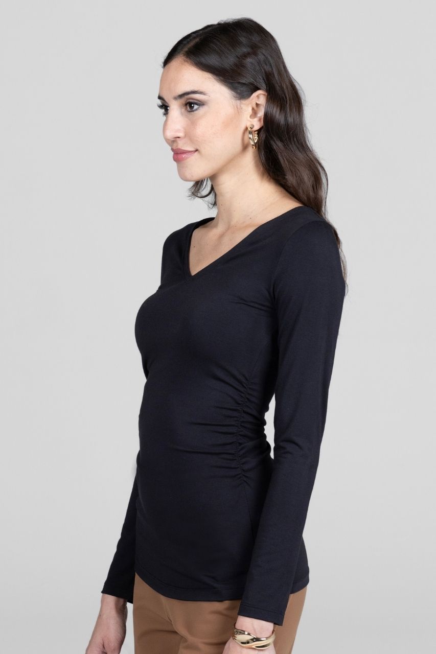 Woman wearing a black long-sleeve top against a plain background