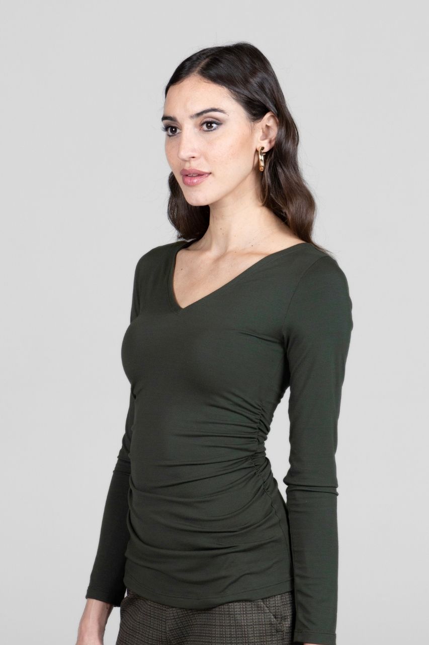 Woman wearing a green long-sleeve top against a plain background