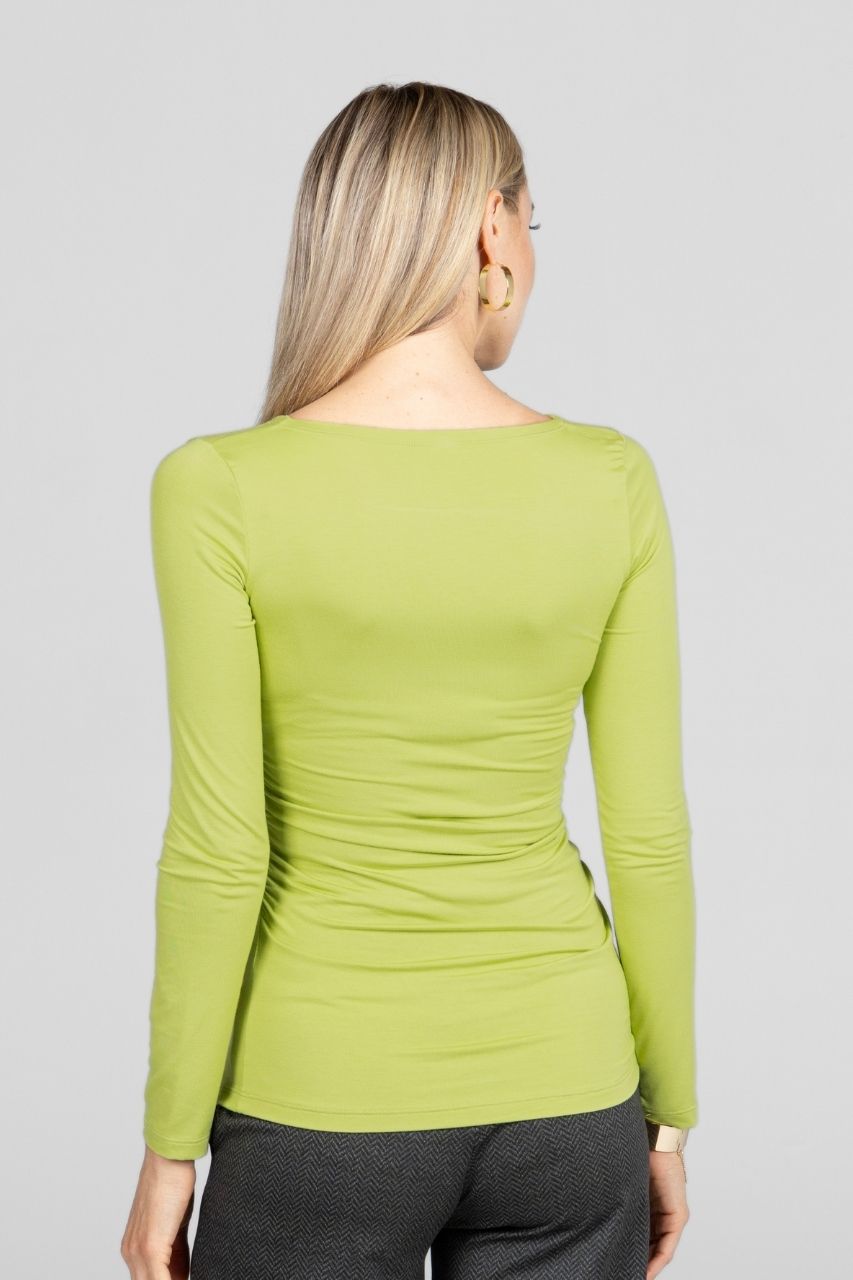 Person wearing a green long-sleeve top on a plain background