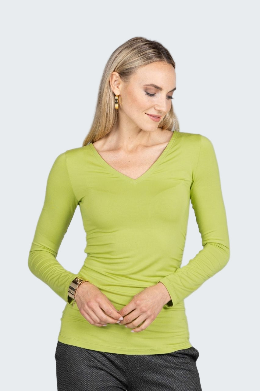 Woman wearing a green long-sleeve top on a gray background