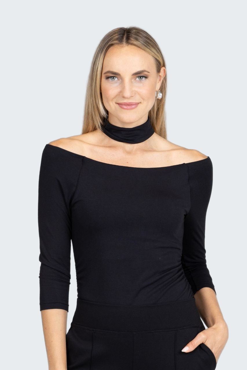 Woman wearing a black off-shoulder top against a gray background