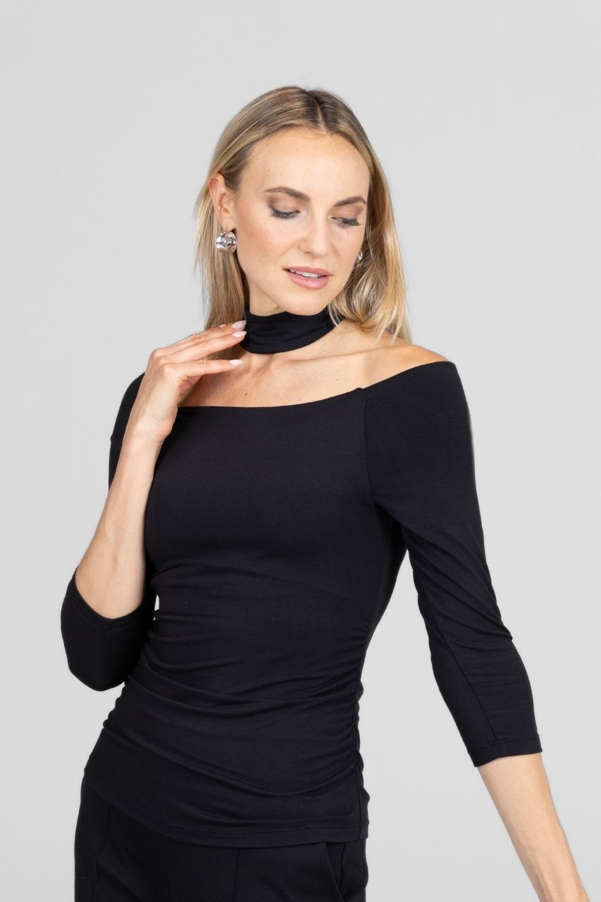 Woman wearing a black off-shoulder top against a gray background