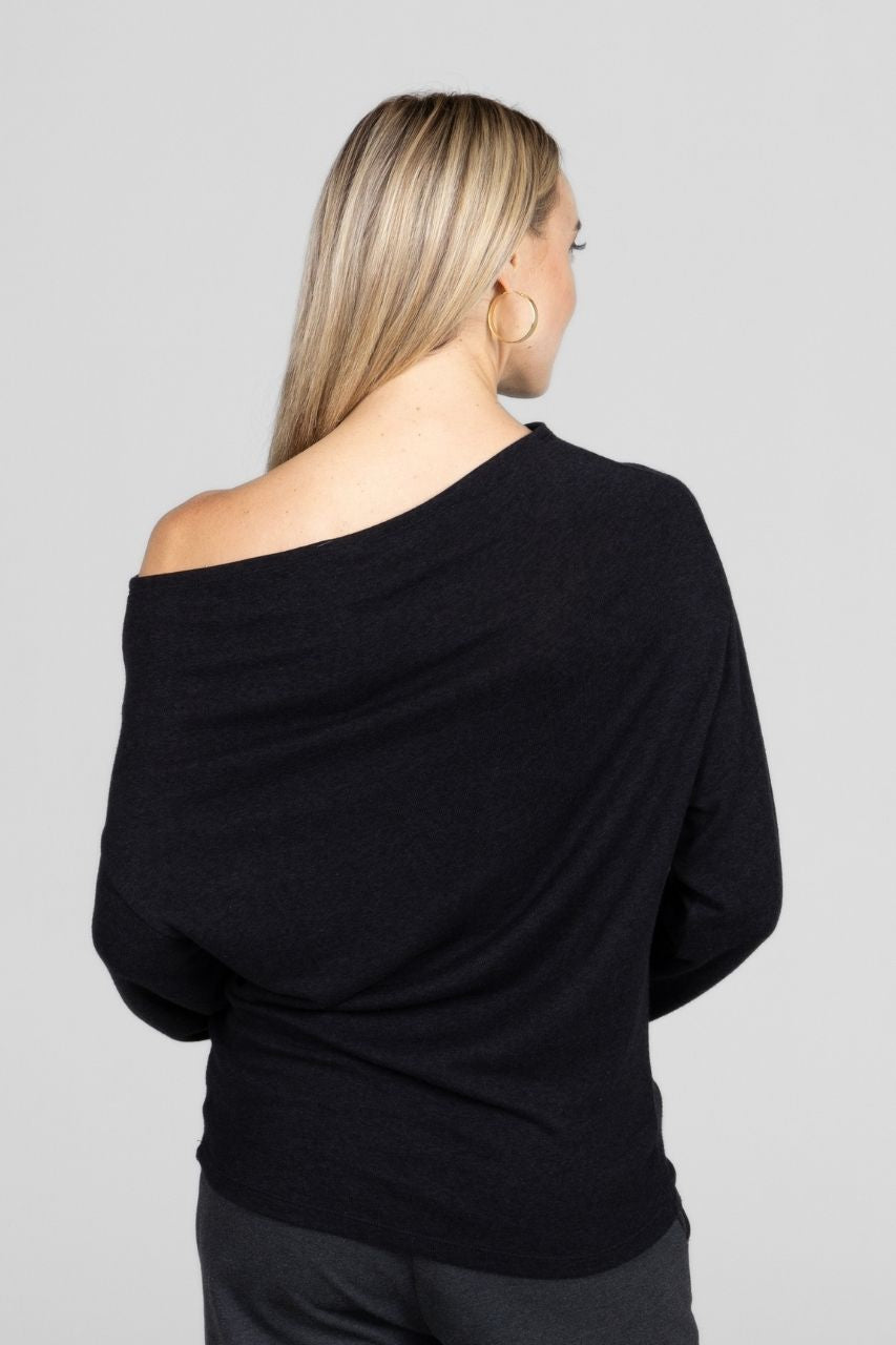 Woman wearing a black off-shoulder top against a gray background
