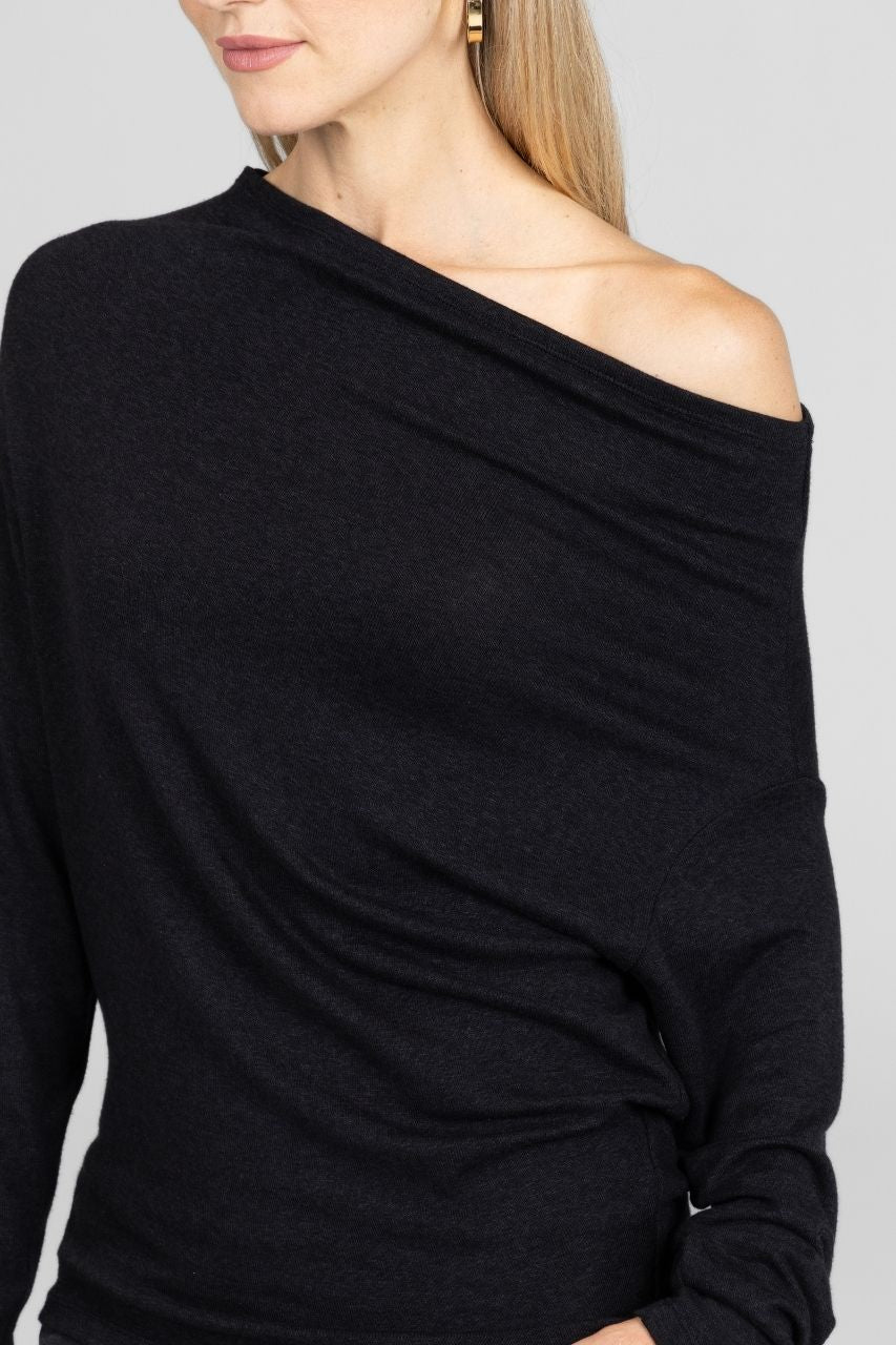 Black off-shoulder sweater worn by a person on a plain background