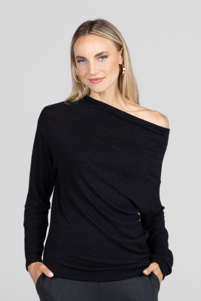 Woman wearing a black off-shoulder top against a gray background
