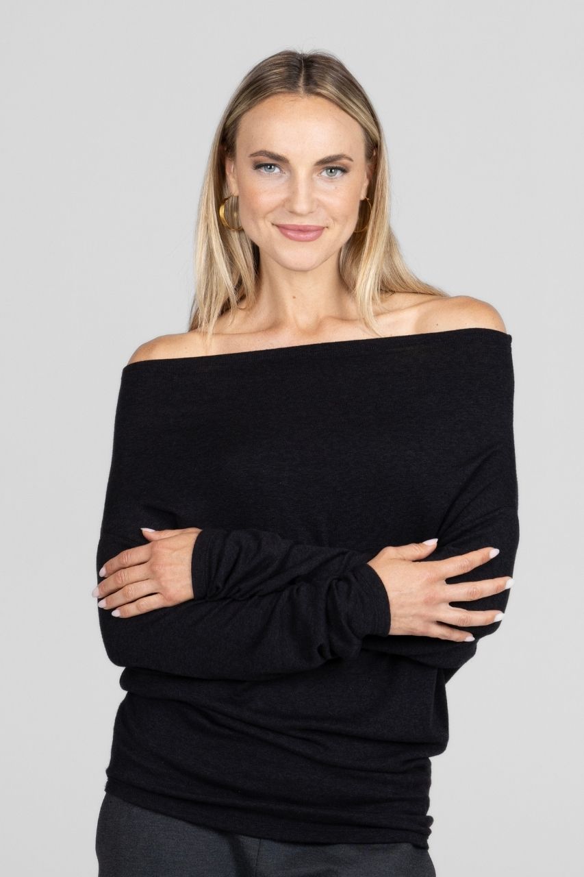 Woman wearing a black off-shoulder sweater against a gray background