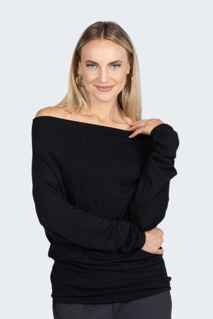 Woman wearing a black off-shoulder top against a plain background