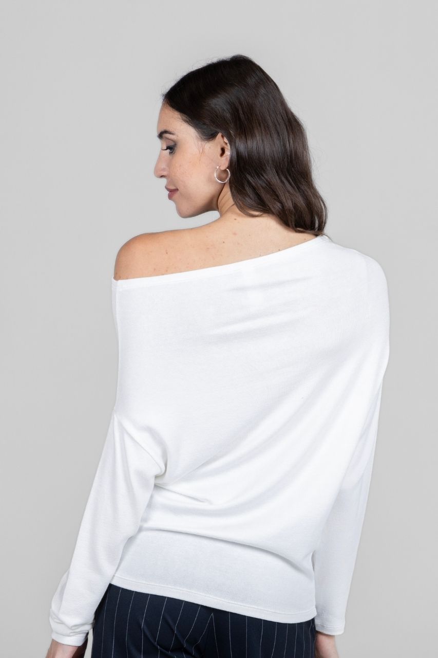 Woman wearing a white off-shoulder top against a gray background