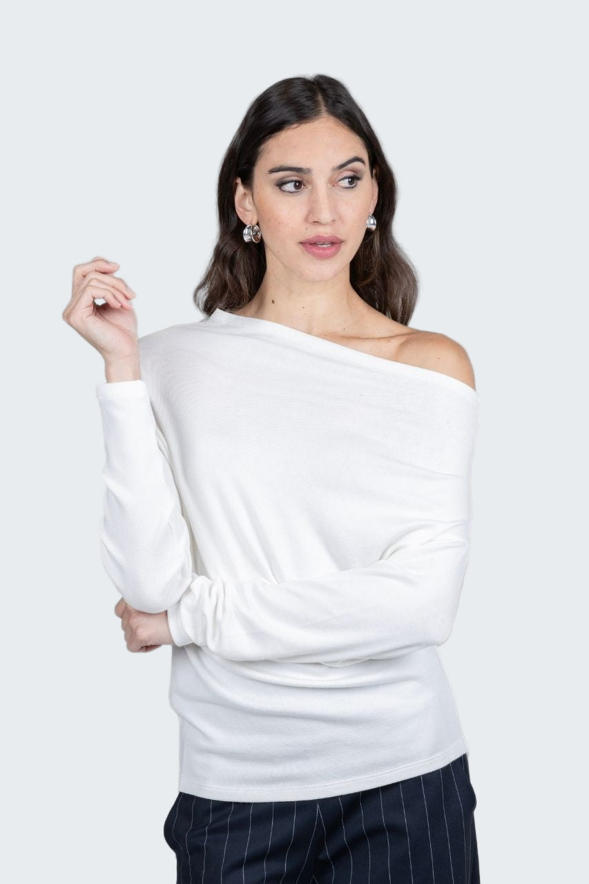Woman wearing a white off-shoulder top against a gray background