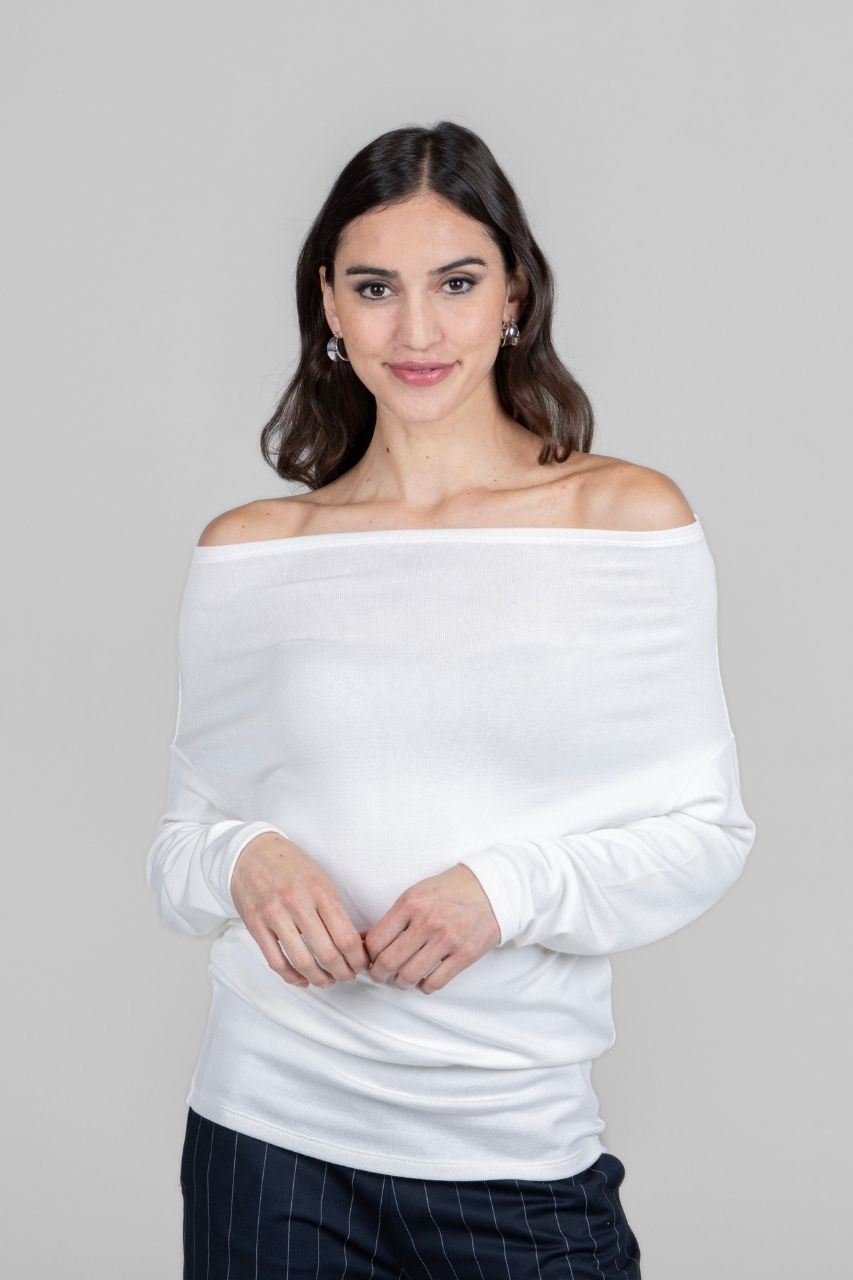 Woman wearing a white off-shoulder top against a gray background