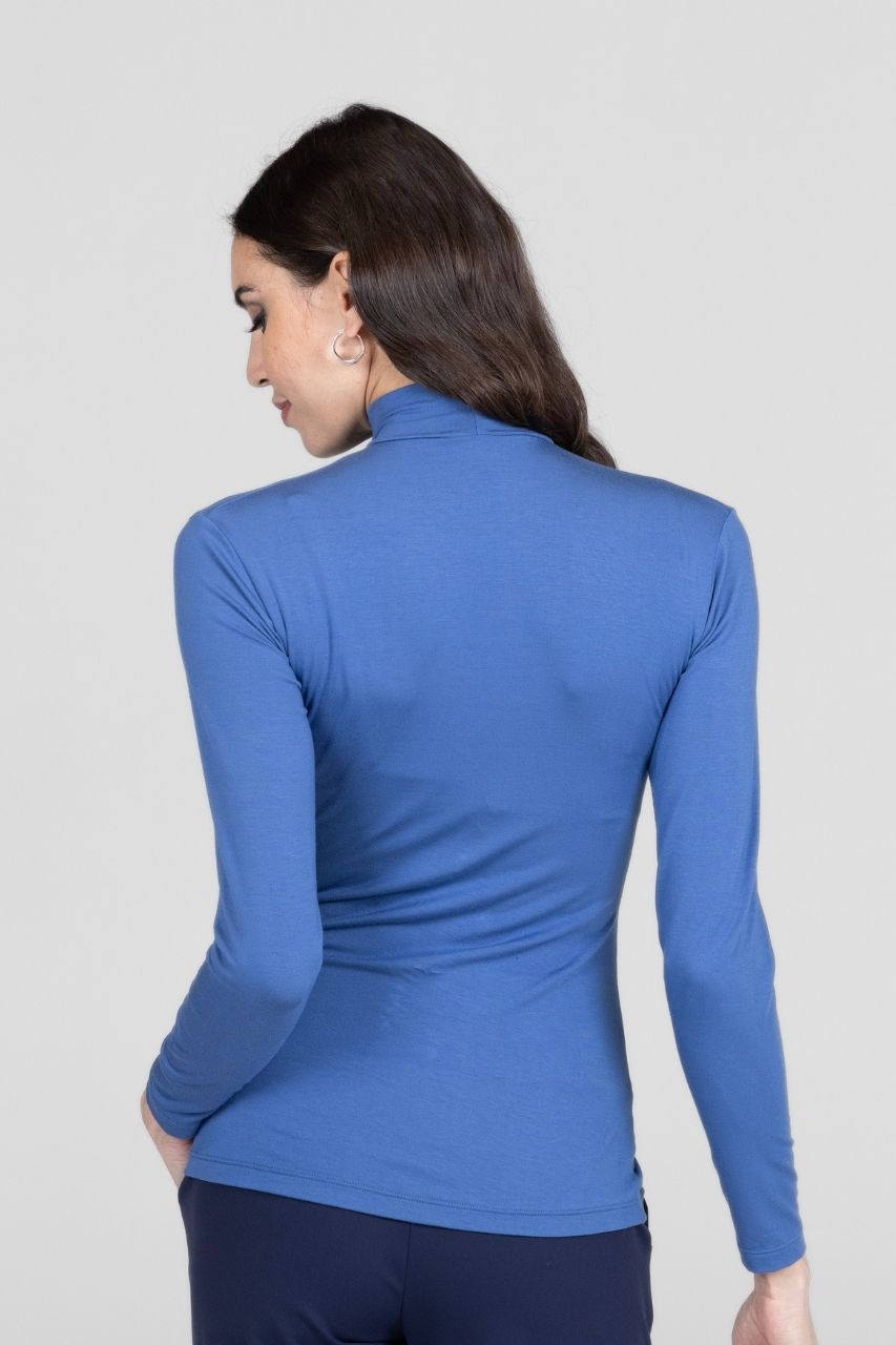 Woman wearing a blue long-sleeve top against a light gray background