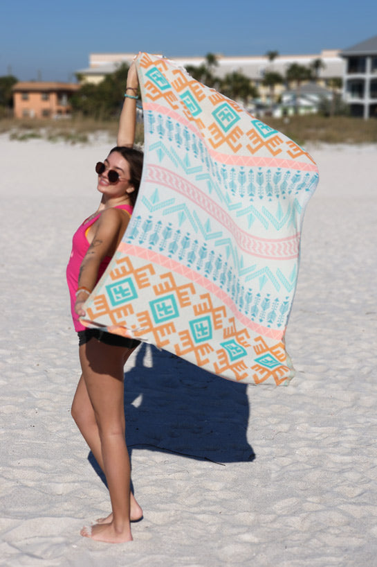 Woman holding a colorful patterned towel on a beach